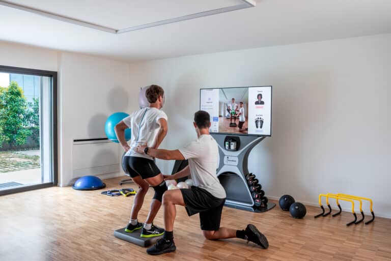 Photo d'une séance à domicile devant son téléviseur assisté par un coach en physique.